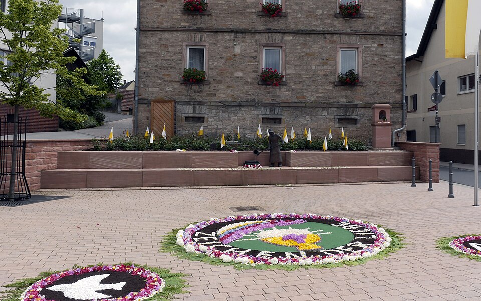 Umzug von Laufach nach Zypern per Palette: Lindenplatz (Lenne) an Fronleichnam in Laufach – Foto: hwhlaufach, CC BY 3.0, via Wikimedia Commons Umzug von Laufach nach Zypern per Palette: Lindenplatz (Lenne) an Fronleichnam in Laufach